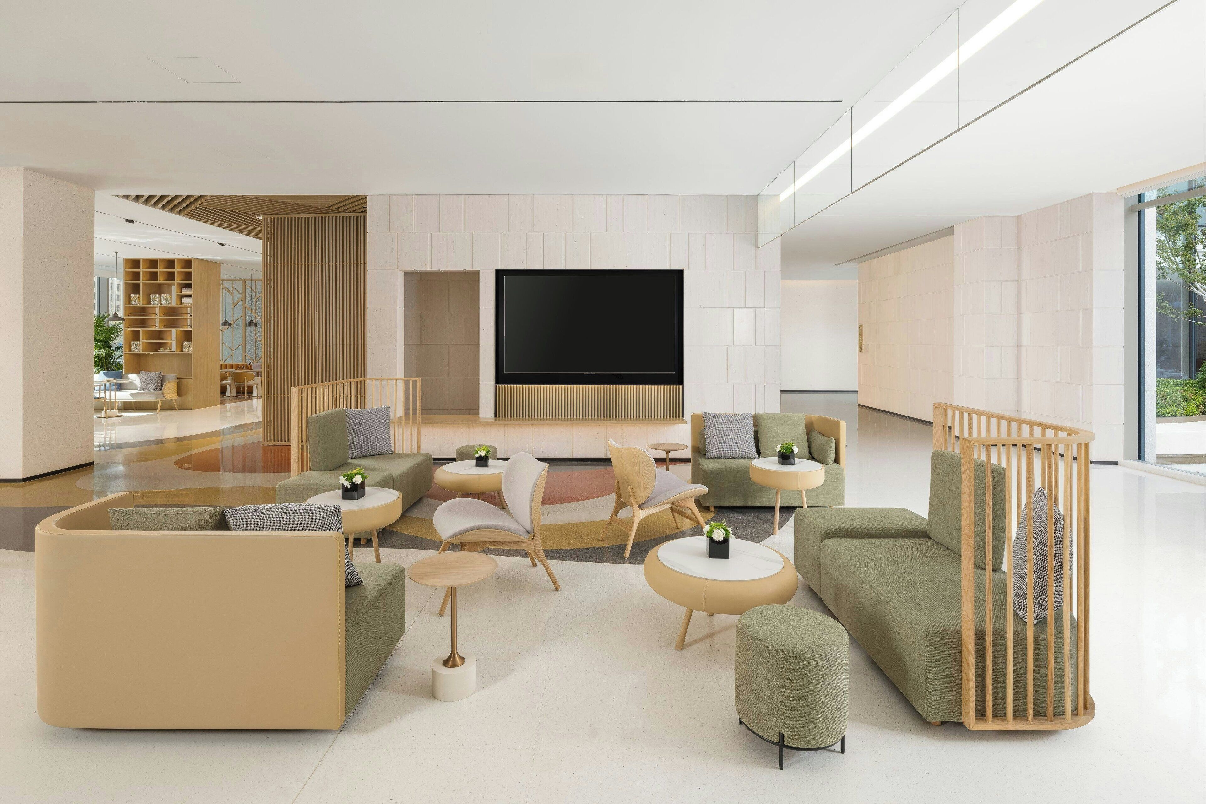 A modern living room with a large flat-screen TV, comfortable seating, and a glass partition.