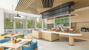 Un espace repas moderne doté d’un îlot central, de différents types de sièges et offrant une vue sur l’extérieur.