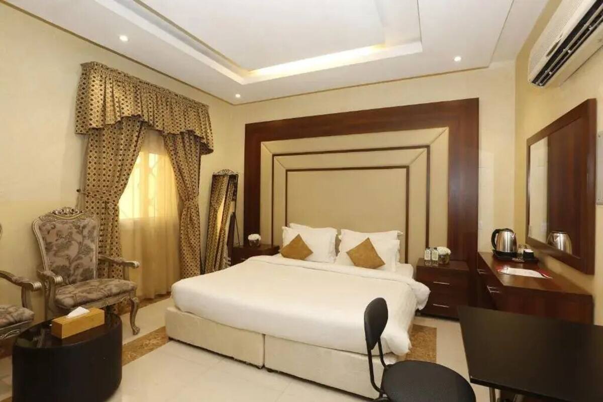 Ein Hotelzimmer mit einem großen Bett, einem Holzkopfstück, einem Schreibtisch und einem Stuhl.