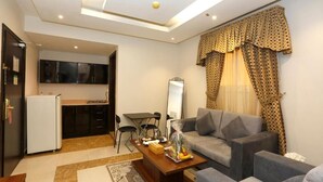 A compact living space with a kitchenette, a sofa set, and a dining table. - Hotelier Suites by Cantonal (Riyadh)