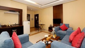 A modern living room with a sofa set, a coffee table, and a television. - Hotelier Suites by Cantonal (Riyadh)