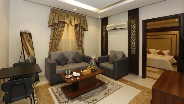 A modern living room with two grey sofas, a coffee table, and a dining area with a black table and chairs. - Hotelier Suites by Cantonal (Riyadh)