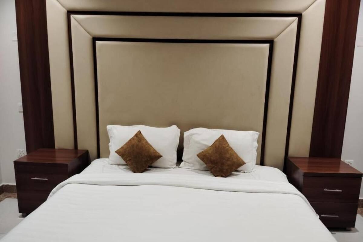 Ein Schlafzimmer mit einem großen Bett, zwei Nachttischen und einem Kopfteil mit geometrischem Muster.