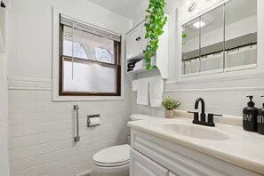Een moderne badkamer met toilet, wastafel en spiegel.