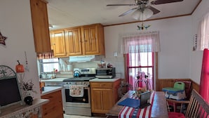 A kitchen with wooden cabinets, a stove, a microwave, and a dining area with a table and chairs.