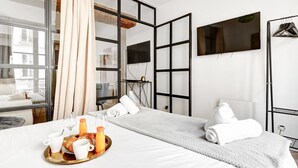Une chambre d’hôtel avec un lit, un plateau de petit-déjeuner, une télévision et une vue sur l’extérieur.