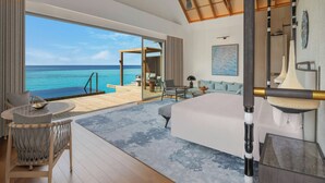 A modern hotel room with a large bed, a seating area with a view of the ocean, and a balcony with outdoor furniture. - JW Marriott Maldives Kaafu Atoll Island Resort (Hathaa Finolhu)