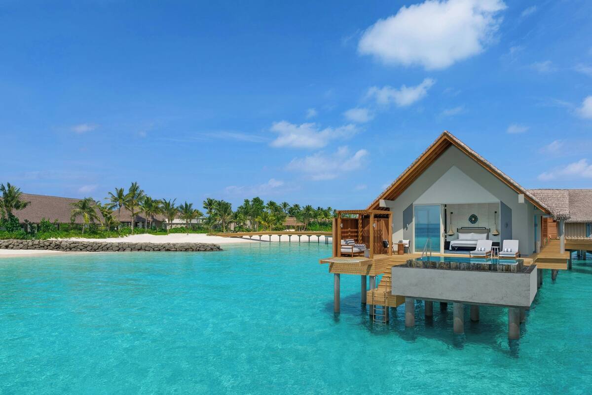 An overwater bungalow with a private pool, wooden deck, and lounge chairs.