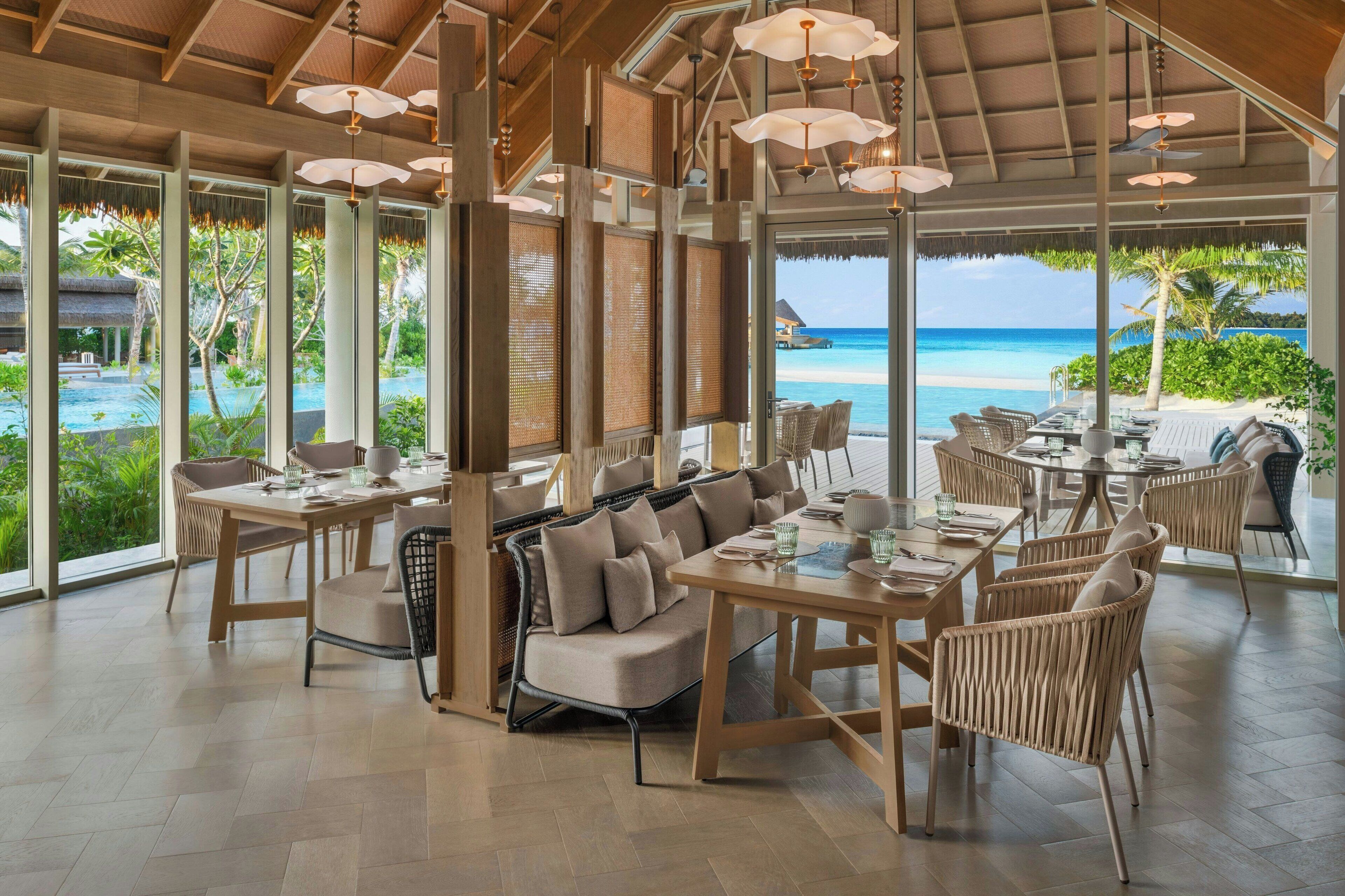 Un comedor amplio con ventanas grandes que ofrecen vista a la playa y al océano.