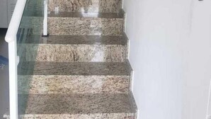 Eine Treppe mit Glasgeländer und einer weißen Wand mit einem grünen Ziertelement.