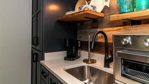 Une cuisine moderne dotée d’un évier en acier inoxydable, d’une machine à café et d’un four encastré.