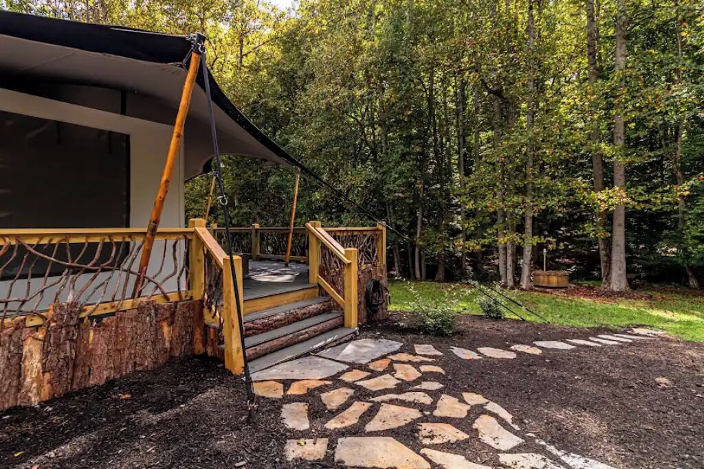 A rustic wooden staircase leading to a covered outdoor area with a stone pathway.