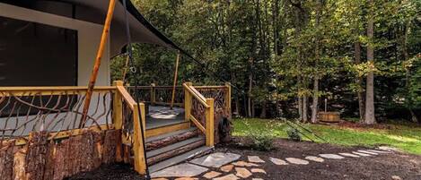 A rustic wooden staircase leading to a covered outdoor area with a stone pathway.