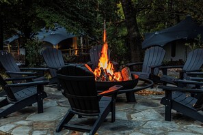 A stone patio with Adirondack chairs arranged around a central fire pit. - NAKUPENDA, a Unique Luxury Canvas Cabin Experience, at Karoo Smith Mountain Lake (Wirtz)