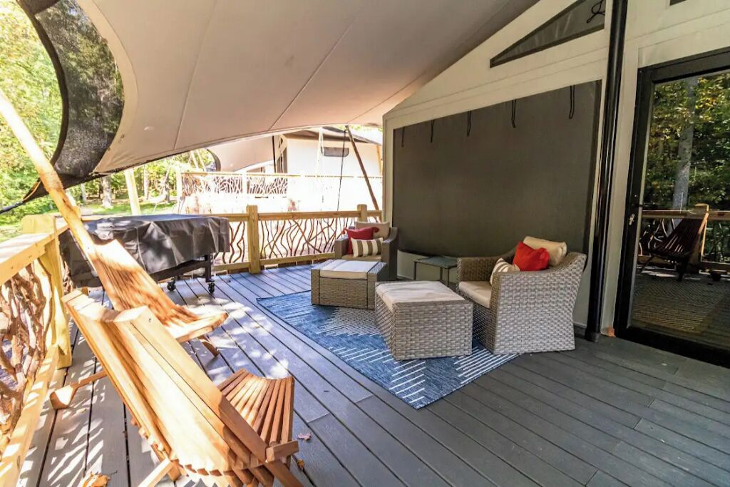 Una terraza exterior con sillones de madera, sofás de mimbre y una zona de barbacoa.