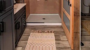 A narrow hallway with a sliding door leading to a shower area.