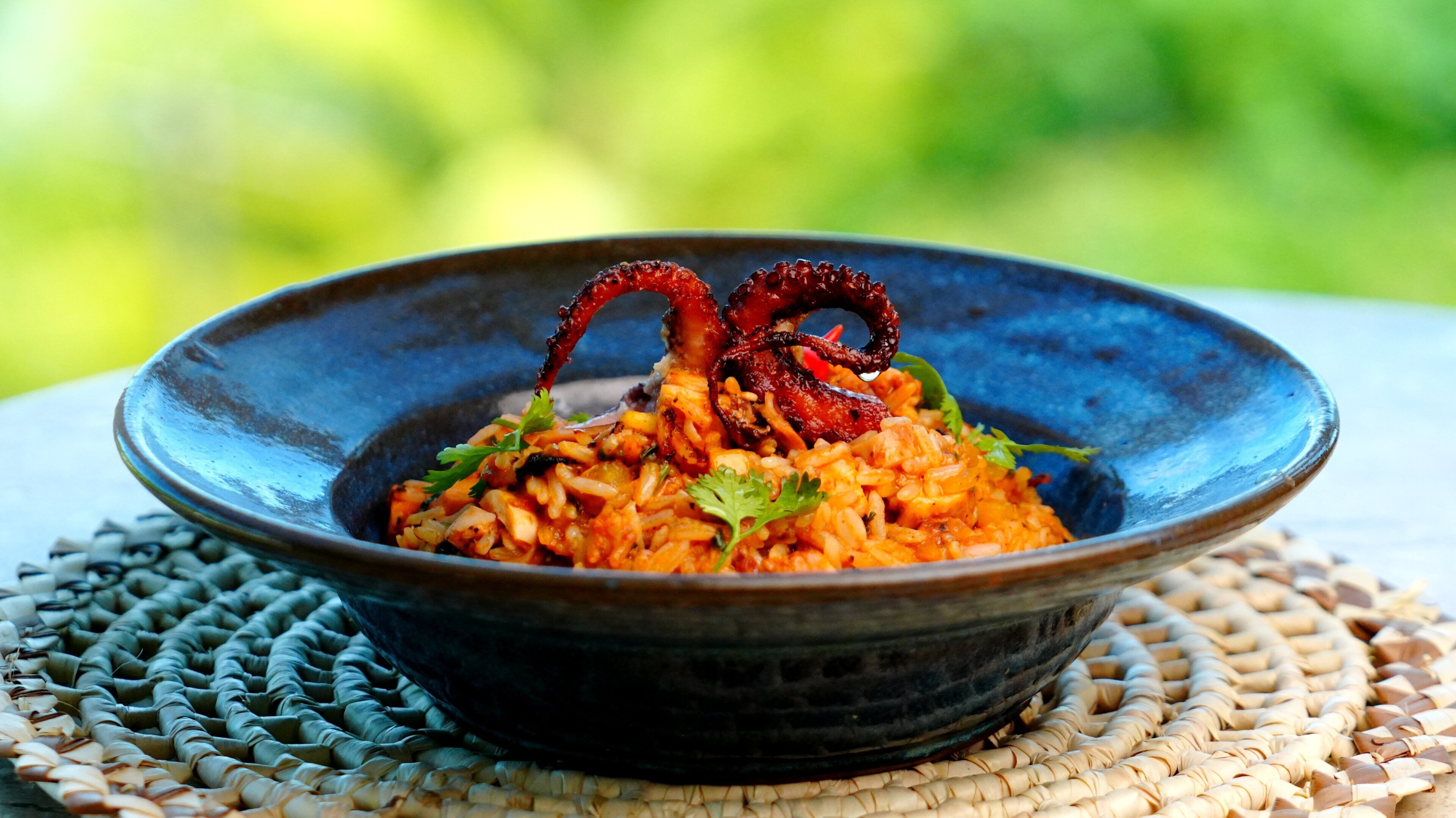 Un bol de riz accompagné de légumes et de quelques garnitures, le tout posé sur un napperon tissé.