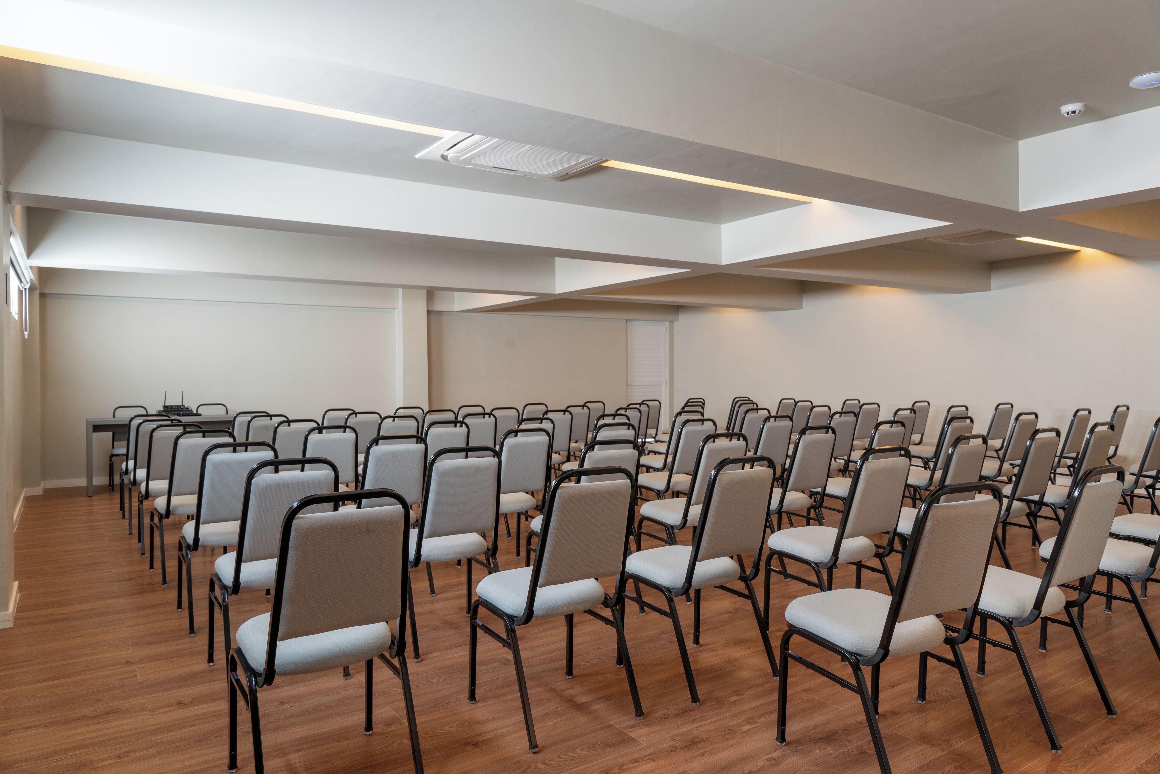 A conference room with rows of chairs and a wooden floor.