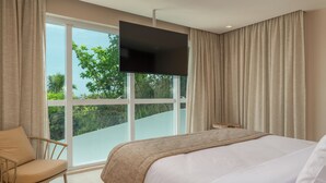 Un dormitorio con una cama grande, un televisor montado en la pared y vistas al exterior.