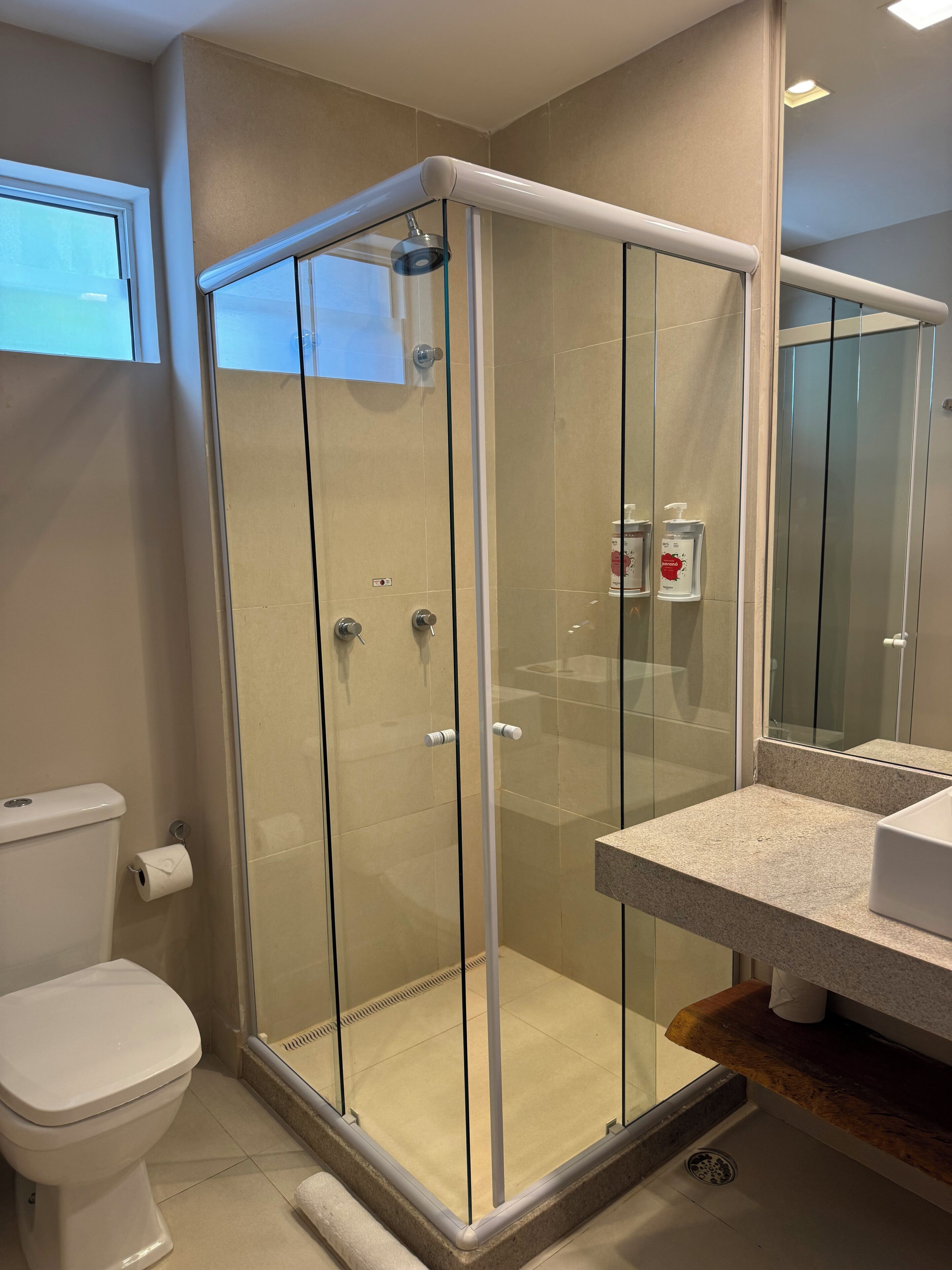 Ein modernes Badezimmer mit einer gläsernen Dusche, einer Toilette und einem Waschtisch mit Spiegel.