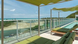 A balcony with a glass railing overlooking a pool and beach. - Transamerica Dunas de Marapé - Alagoas (Coruripe)