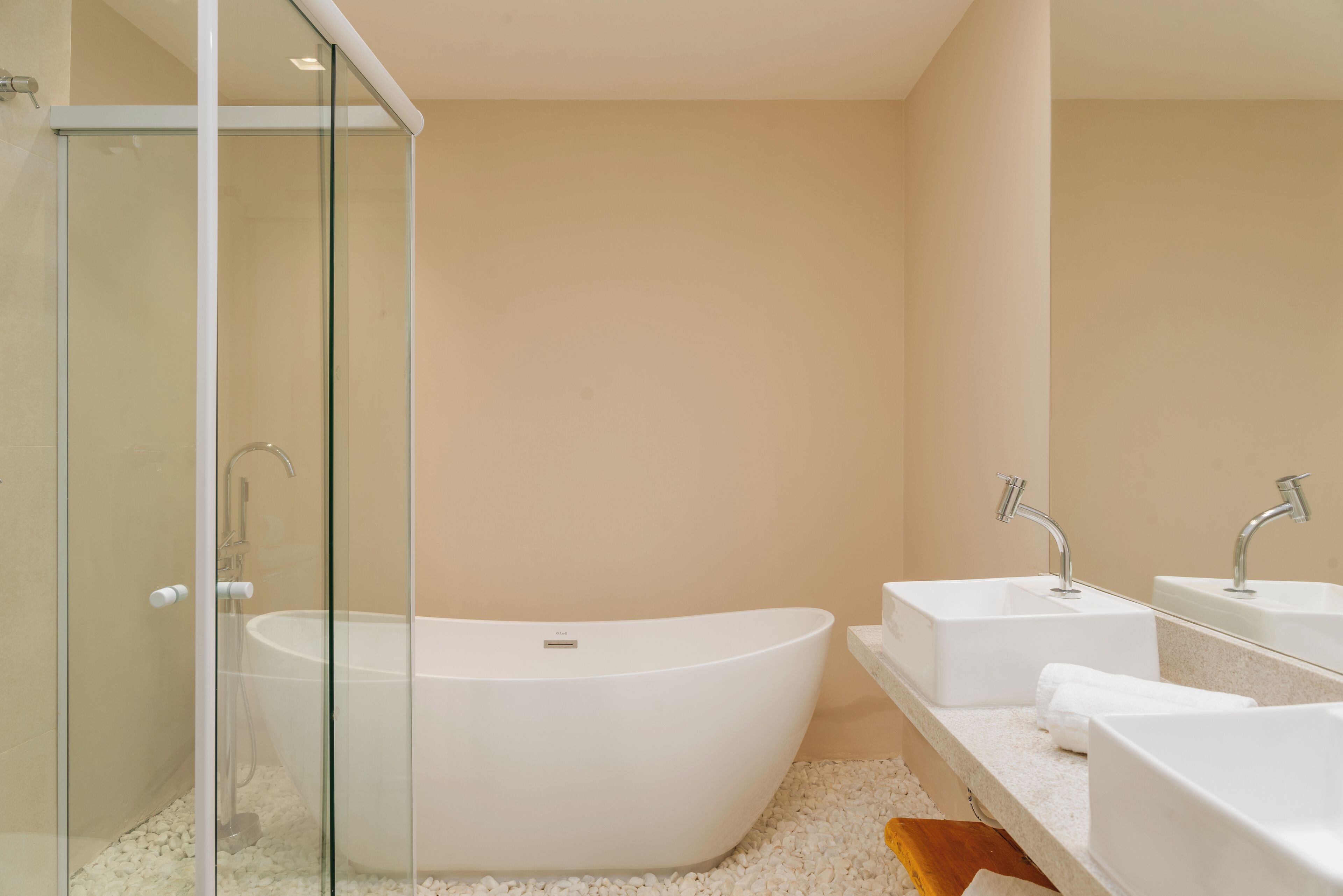 Une salle de bain moderne avec une baignoire sur pieds, une douche à parois de verre et deux vasques avec des miroirs.