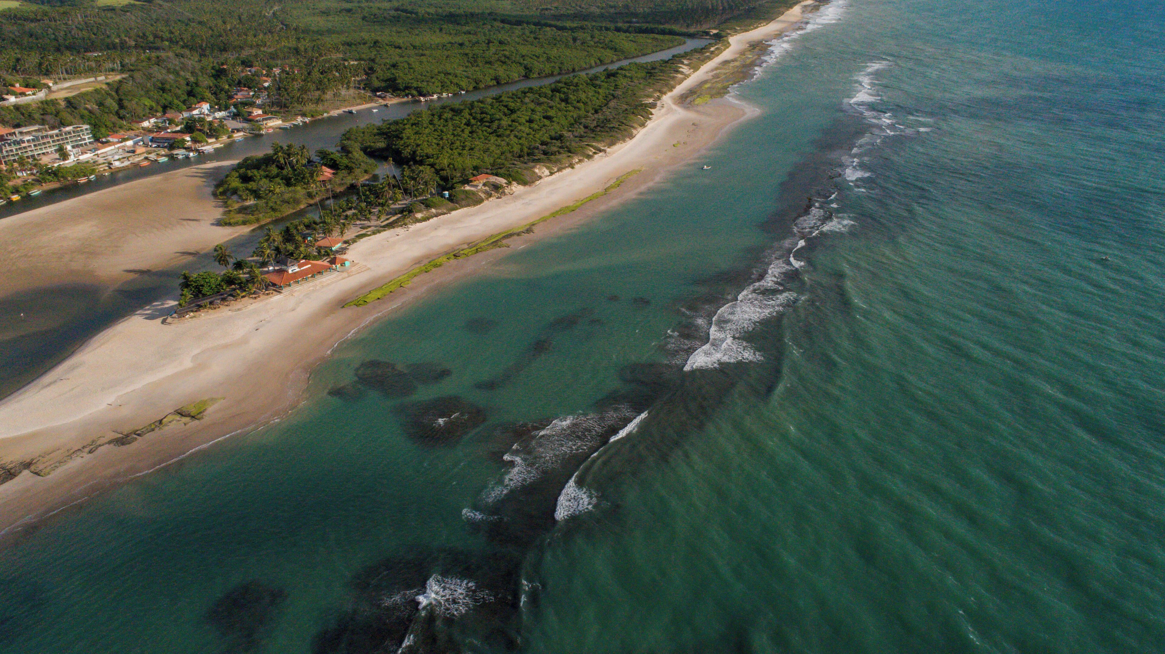Eine Luftaufnahme einer Küstenlandschaft mit Strand, Fluss und bewaldetem Gebiet.