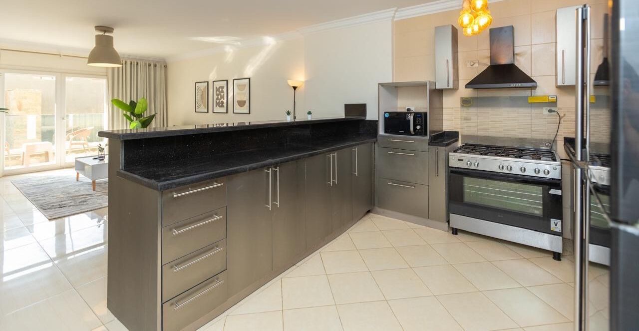 A modern kitchen with a central island, stainless steel appliances, and a dining area with a view.
