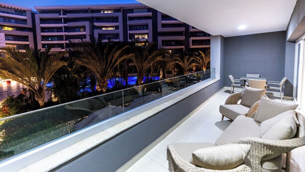 A balcony with wicker furniture and a view of a building with multiple floors. - Ocean Apartments (Cairo)