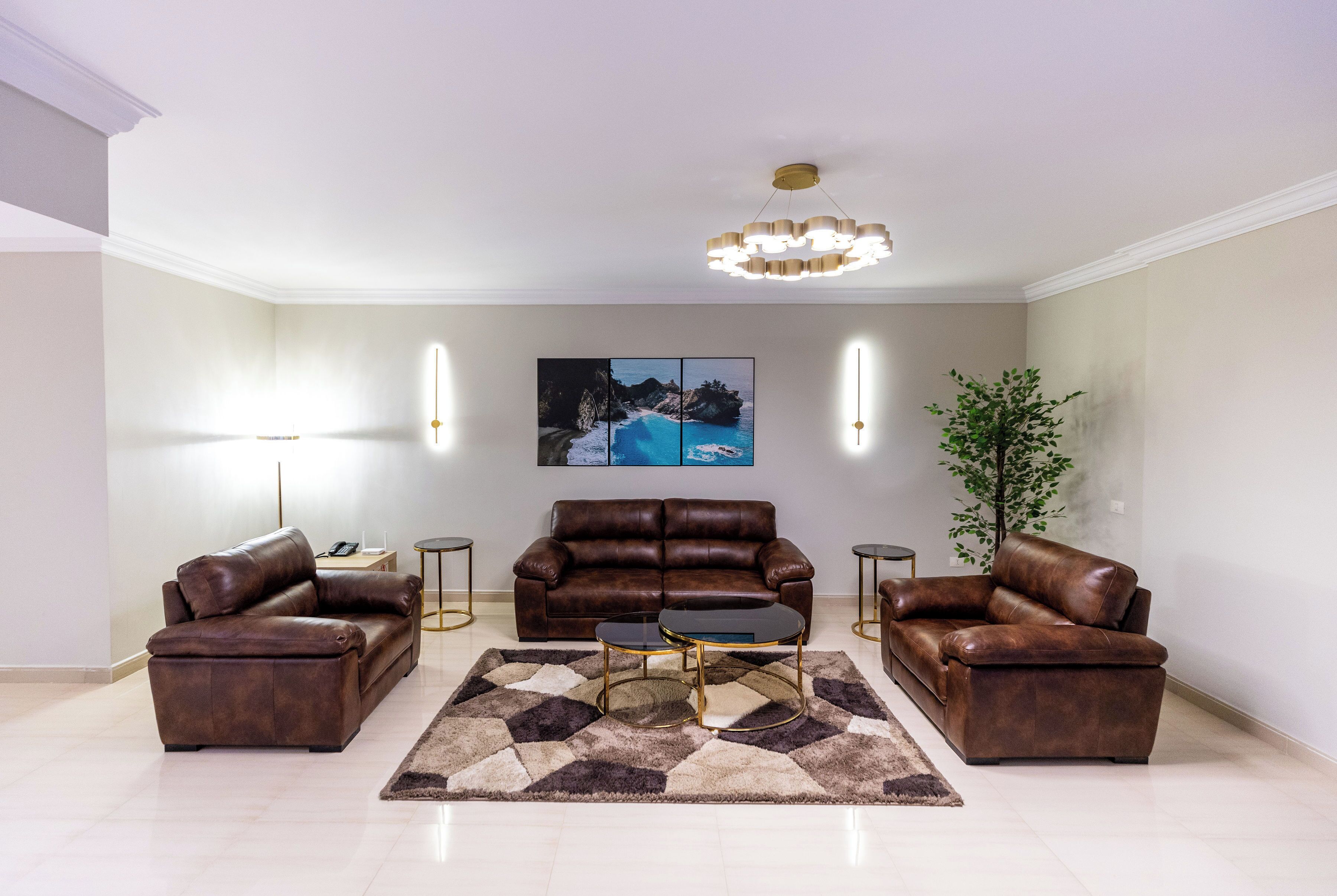 A modern living room with a brown leather sofa set, a coffee table, and a large painting on the wall.