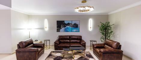 A modern living room with a brown leather sofa set, a coffee table, and a large painting on the wall.