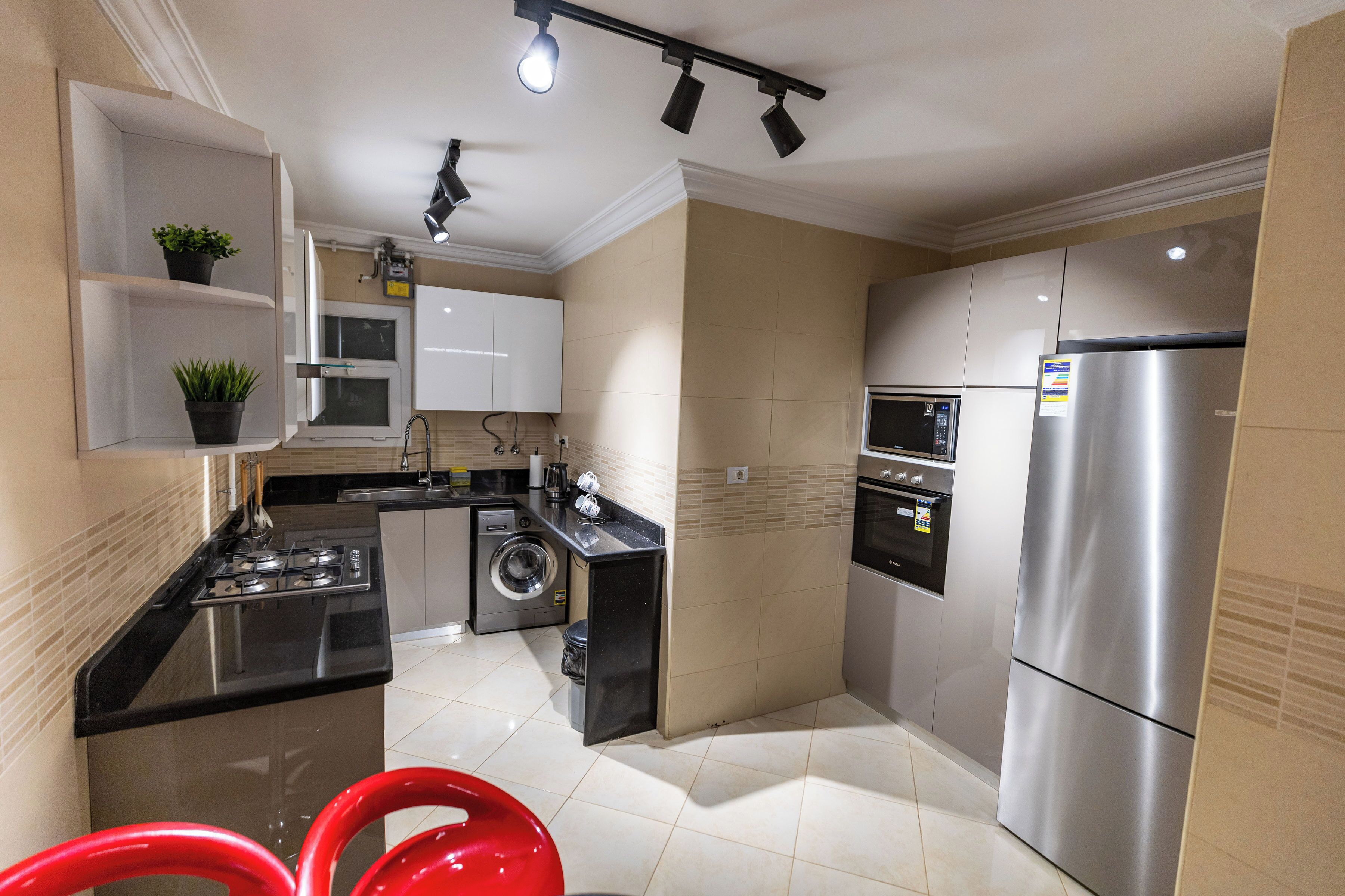 A modern kitchen with stainless steel appliances, a washing machine, and a built-in oven.