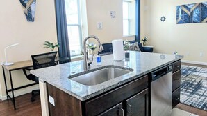 Una cocina moderna con encimeras de granito, un fregadero de acero inoxidable y lavavajillas.