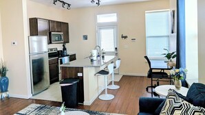 Cocina moderna con refrigerador, microondas y pileta. Hay un comedor con mesa y sillas.