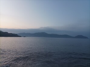 Een rustige zee met verre bergen en een mistige lucht.