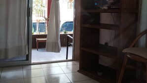 Une pièce dotée d’une porte-fenêtre coulissante donnant sur un balcon, d’un meuble en bois et d’une chaise.