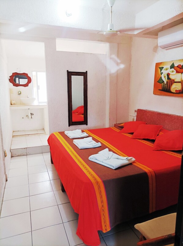 Een hotelkamer met een bed, een badkamer en een schilderij aan de muur.