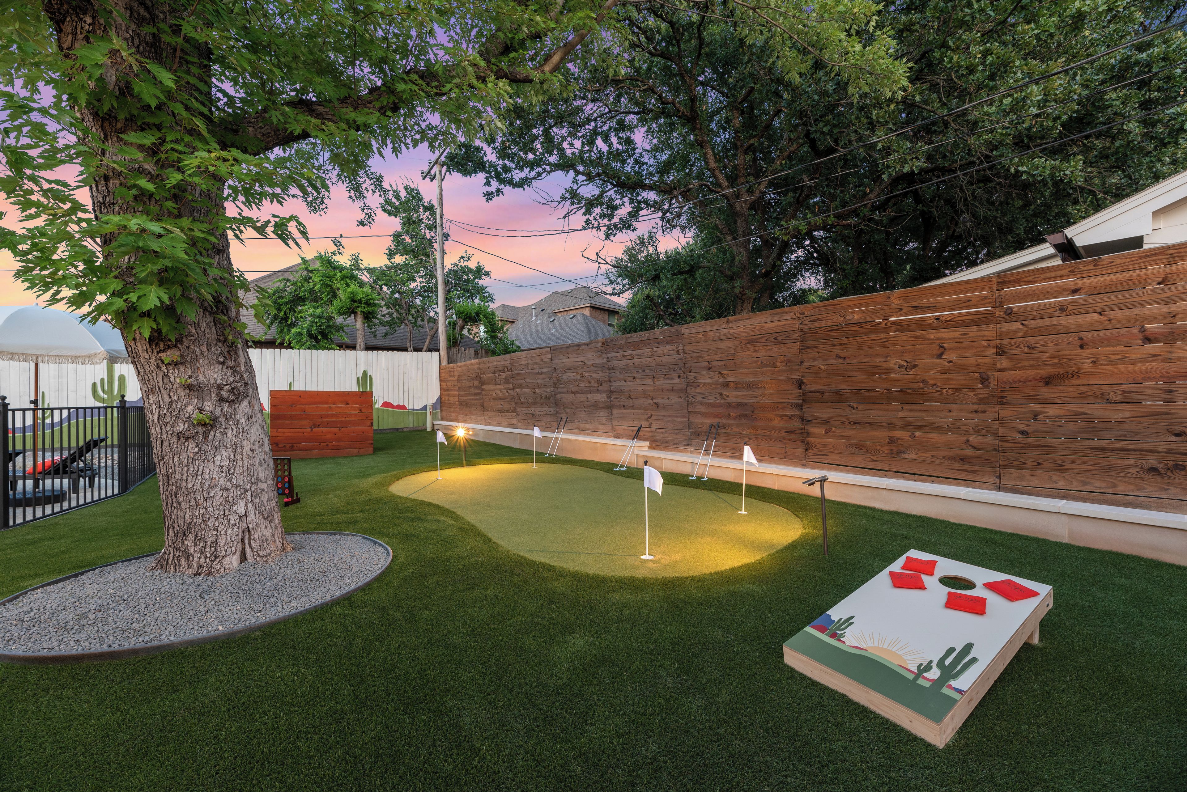 A backyard with artificial grass, a wooden fence, and a wooden play structure.