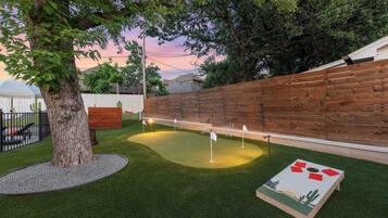 A backyard with artificial grass, a wooden fence, and a wooden play structure.