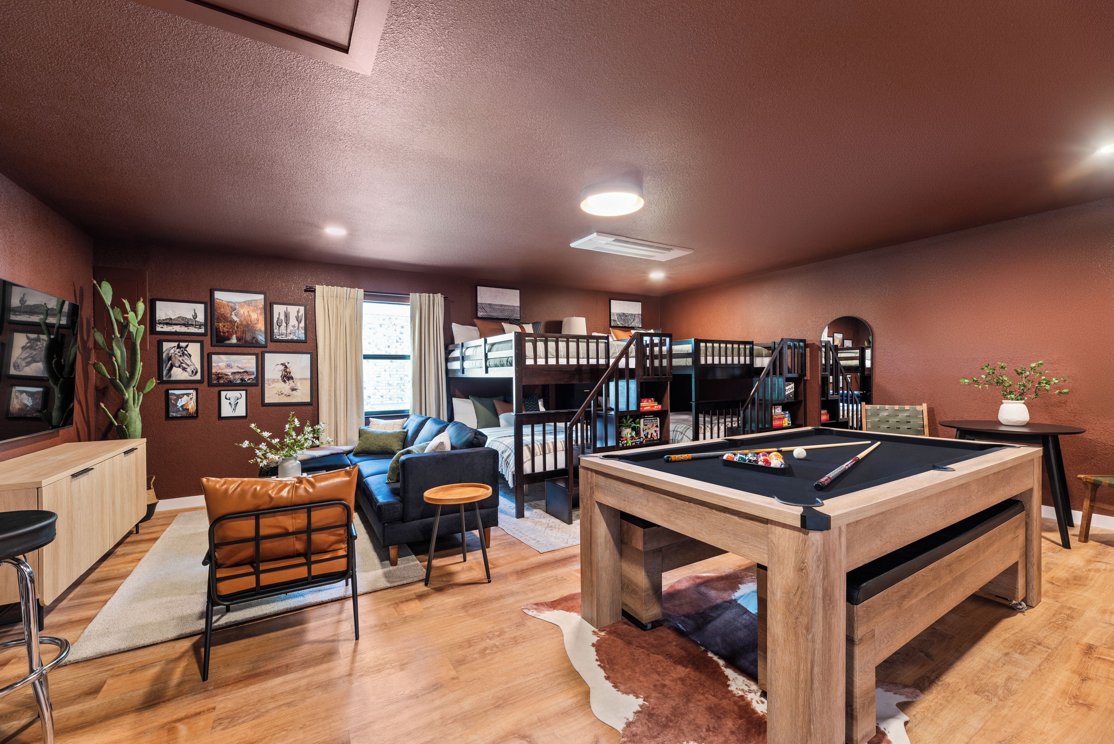 A cozy living area with a pool table, a sofa, a coffee table, and a bookshelf.