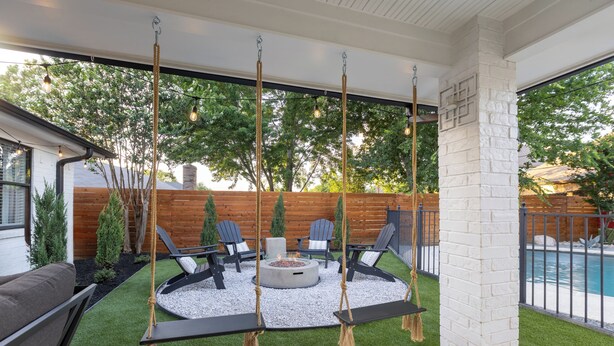 Eine Terrassenfläche mit Schaukel, Sitzgelegenheiten und Feuerstelle.