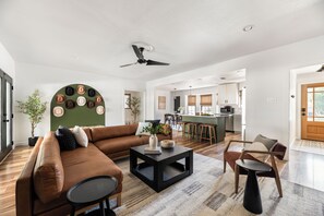 Ein modernes Wohnzimmer mit einem braunen Ledersofa, einem schwarzen Couchtisch und einem Essbereich mit Holzsesseln.