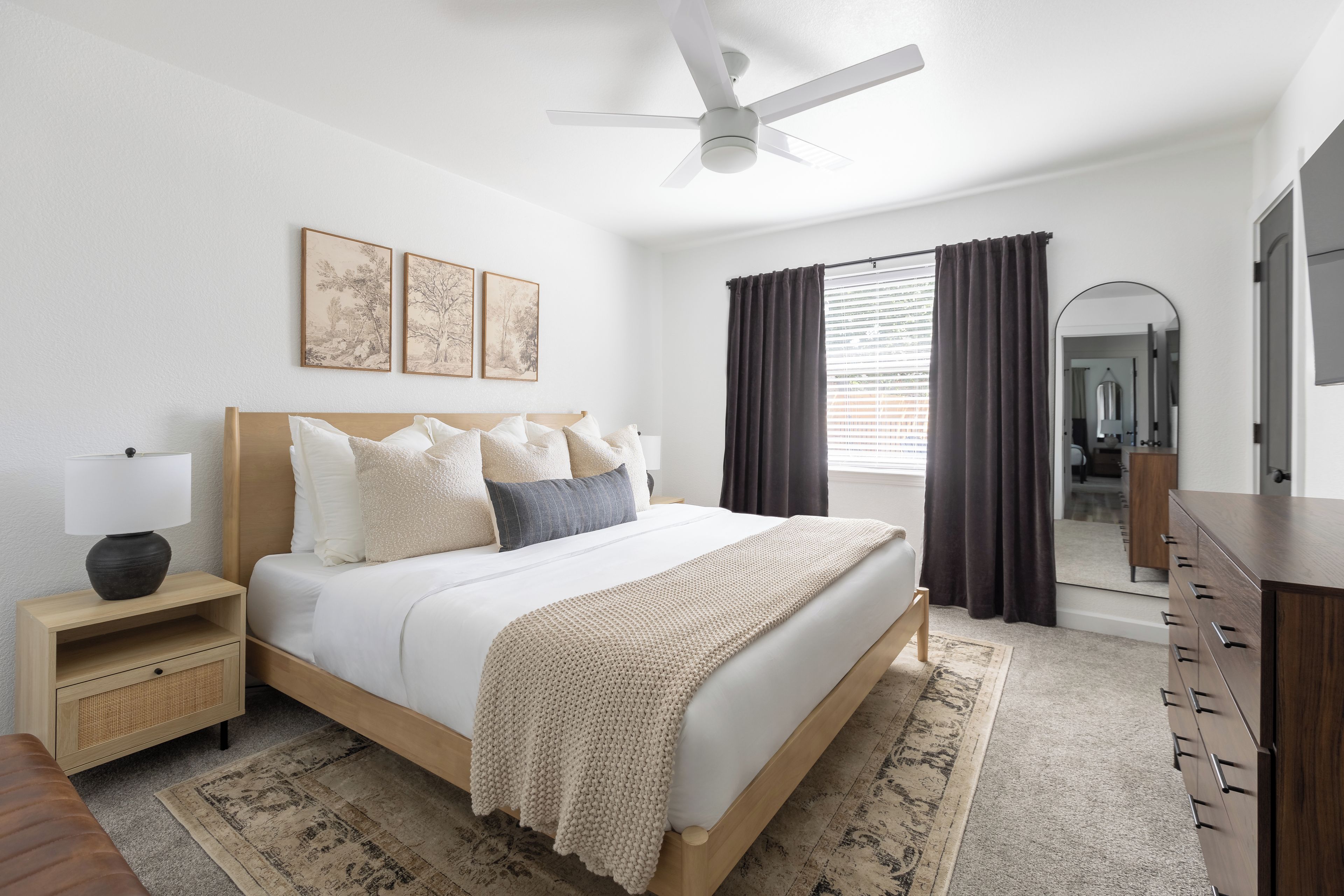 Un dormitorio con cama, mesita de noche, cómoda y ventilador de techo.