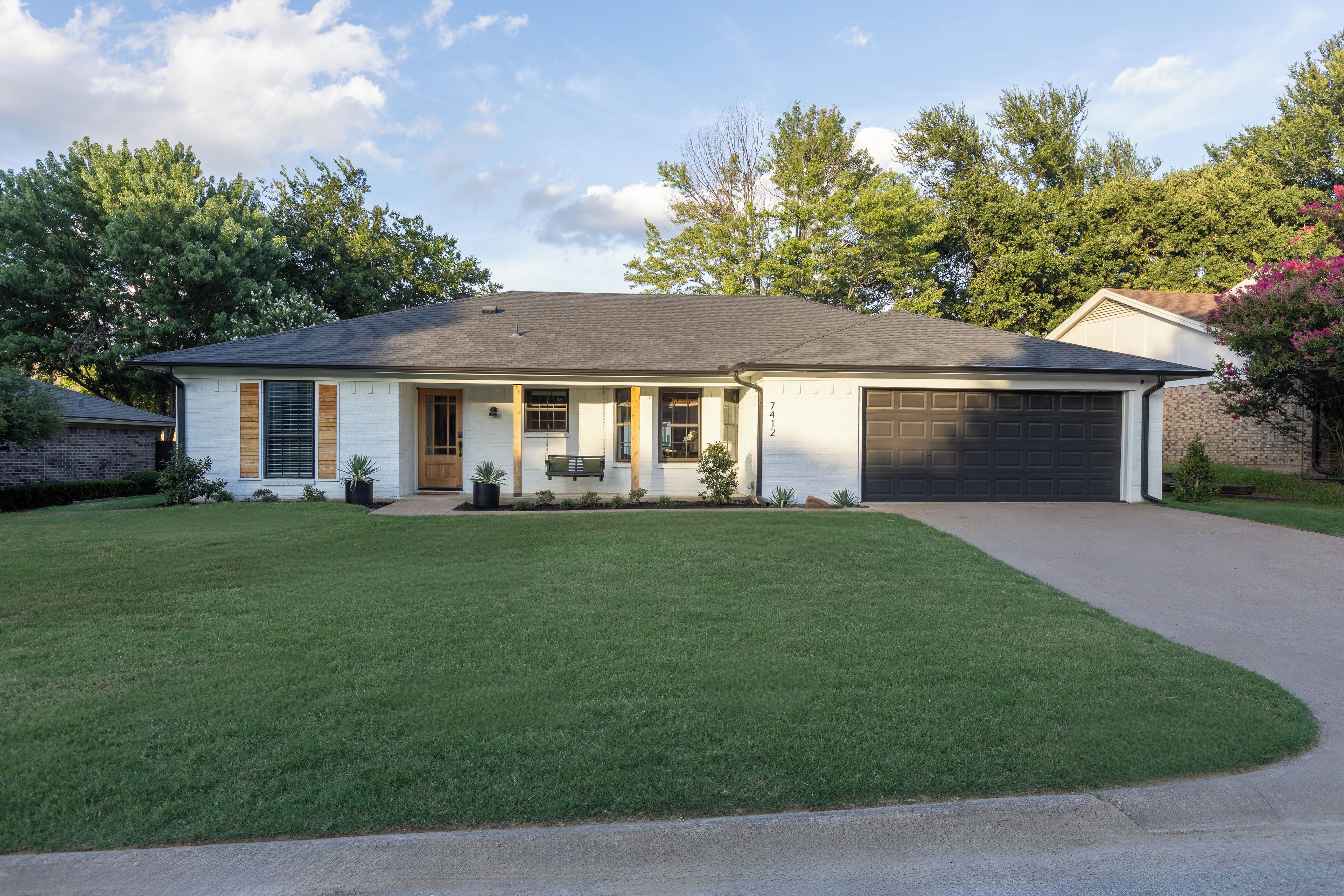 A two-story house with a garage, a front porch, and a well-maintained lawn.