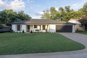 Ein zweistöckiges Haus mit Garage, Veranda und gepflegtem Rasen.