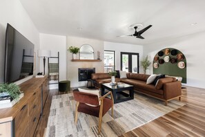 A modern living room with a brown leather sofa, a wooden coffee table, and a TV on a wooden cabinet.