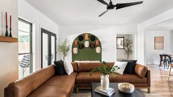 A modern living room with a brown leather sofa, a black coffee table, and a decorative wall piece.