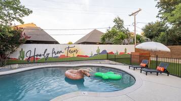 Une piscine ornée d’une fresque murale, de chaises longues et d’une décoration à thème de cactus.