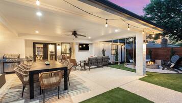 An outdoor patio with a dining table, chairs, and a grill area.
