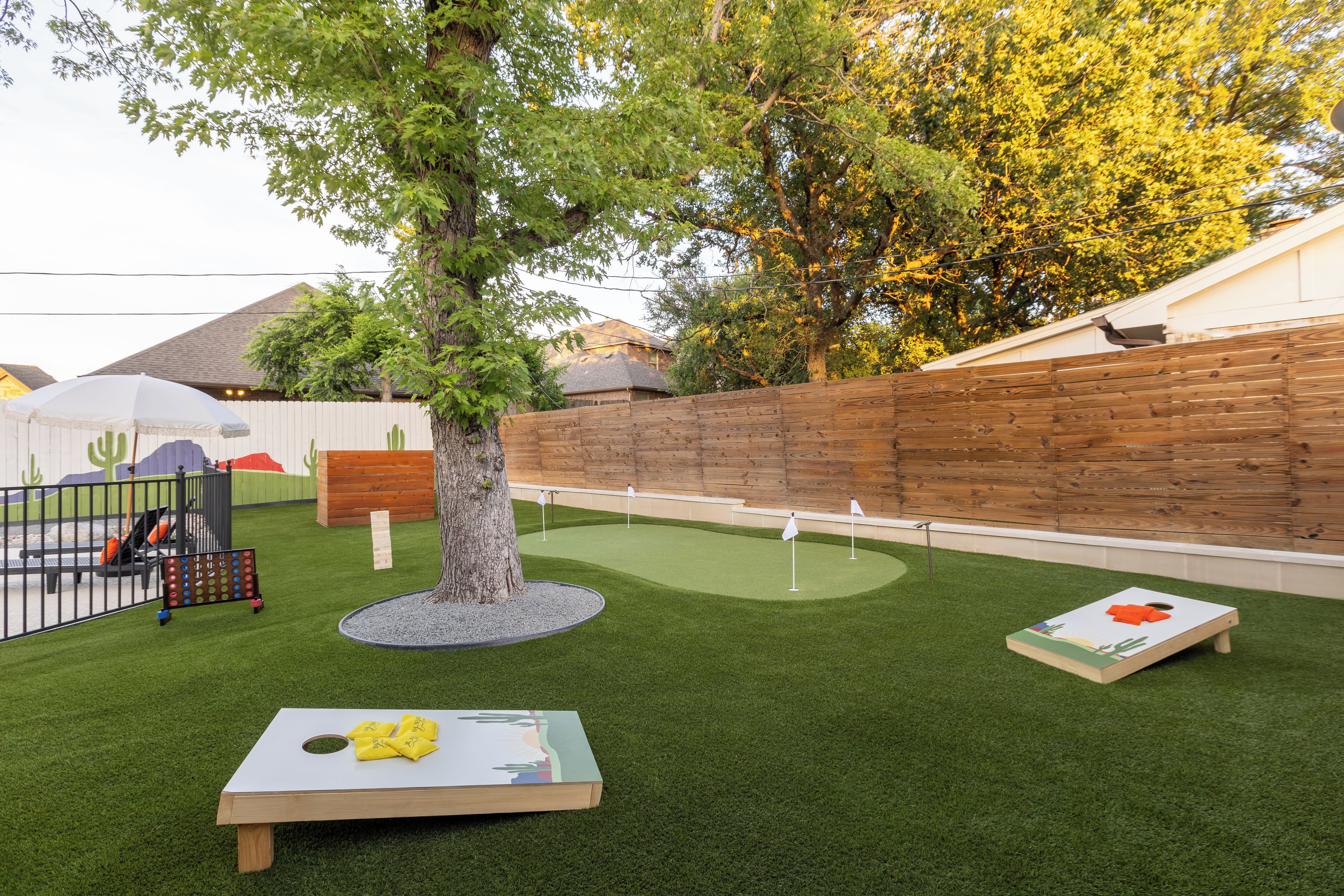 Ein Minigolfplatz mit Holzzaun, Baum und kleinem Tisch mit einer Flagge.